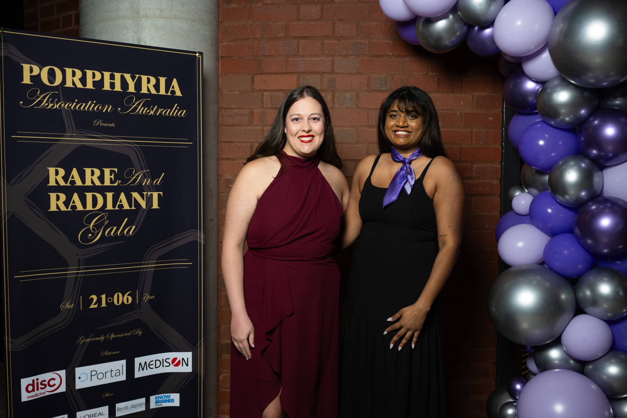 Two guests at the media wall, purple ribbon on show