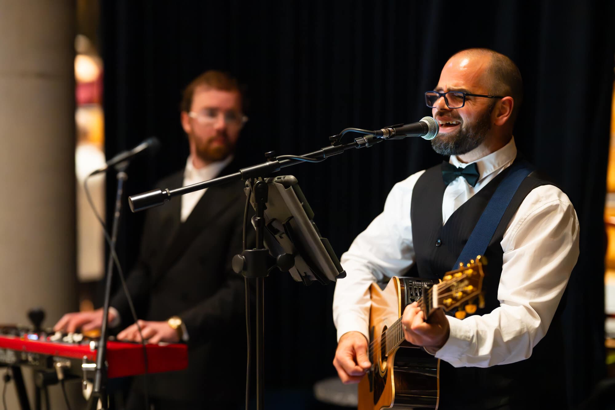The live duo mid-song — guitarist singing with keys behind